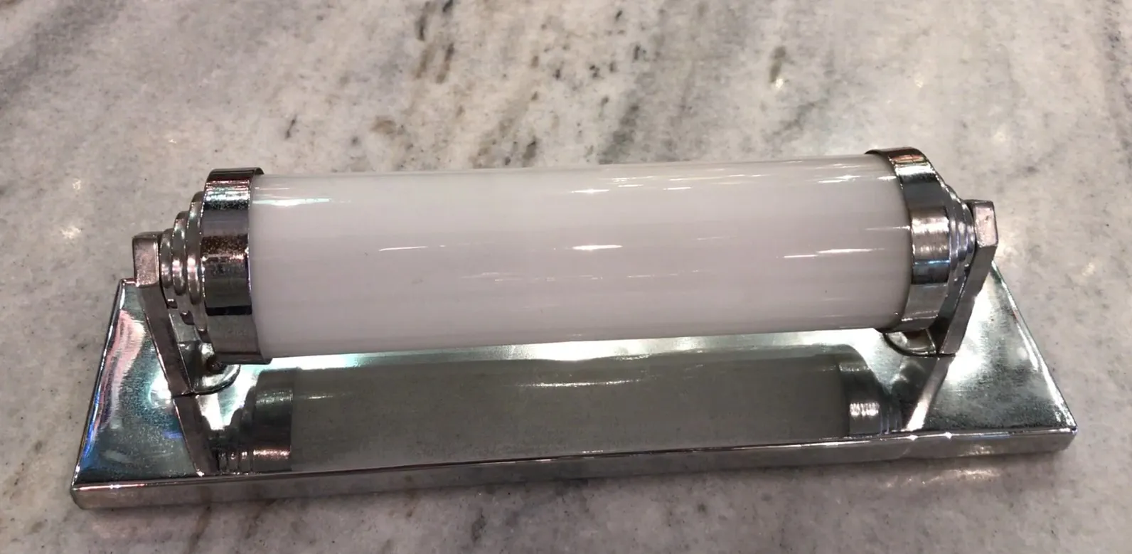 Coppia di applique antiche con luce bianca, stile classico, su superficie chiara.