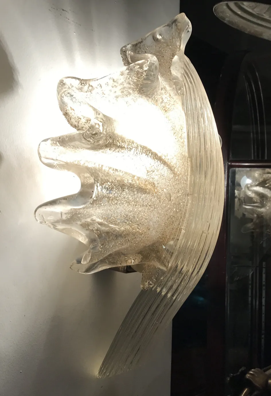 Paire d'appliques anciennes en verre avec lumière chaude et design élégant, embellissant un mur.