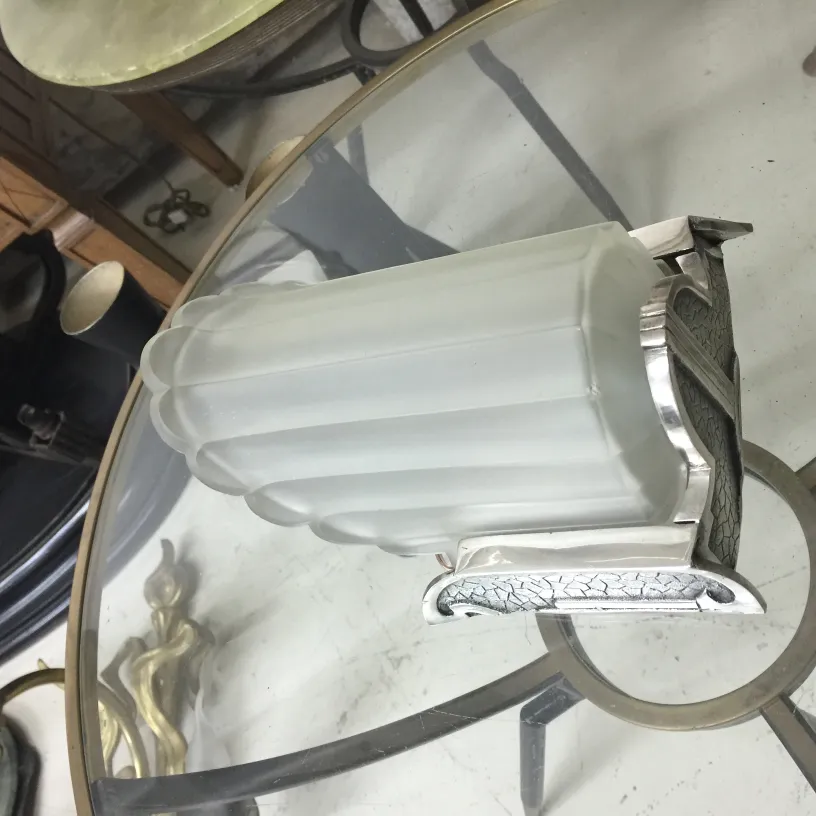 Par de luminárias antigas com base detalhada e vidro fosco, em um ambiente com vários móveis.