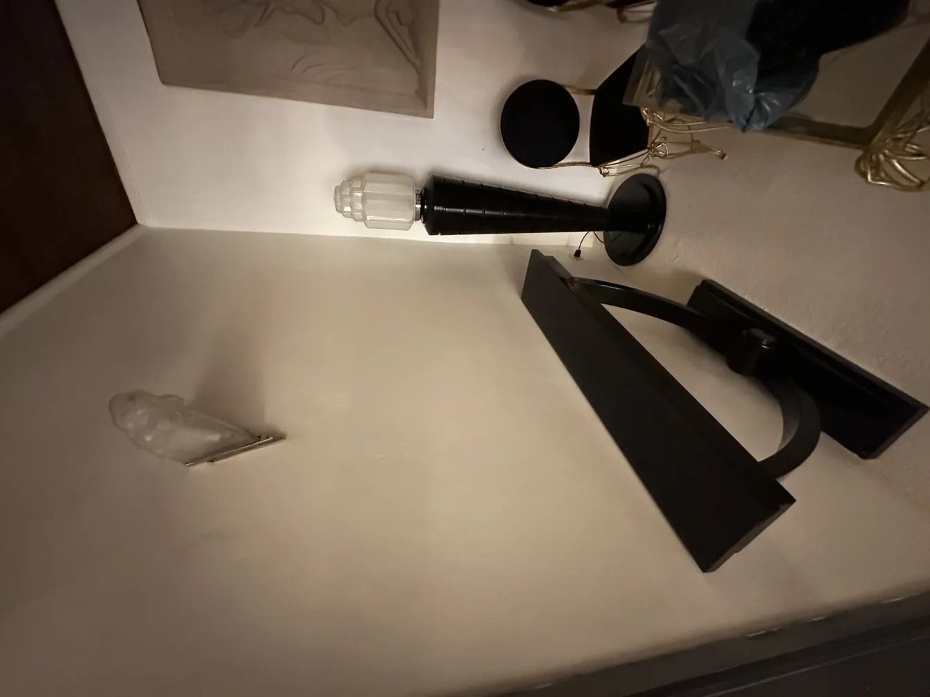 Par de apliques antigos com luz suave em uma parede clara, ao lado de objetos decorativos.