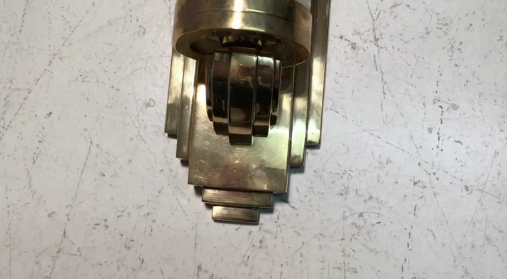 Antique wall sconce with geometric design in golden tones, perfect for elegant decor.