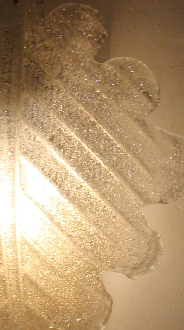 Antike Wandleuchter aus strukturiertem Glas beleuchten eine Wand