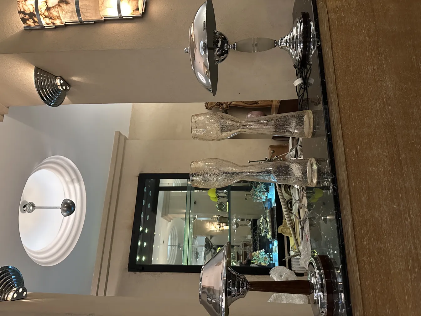 Um par de luminárias de parede antigas com design elegante, iluminando o ambiente. Outros objetos decorativos ao fundo.