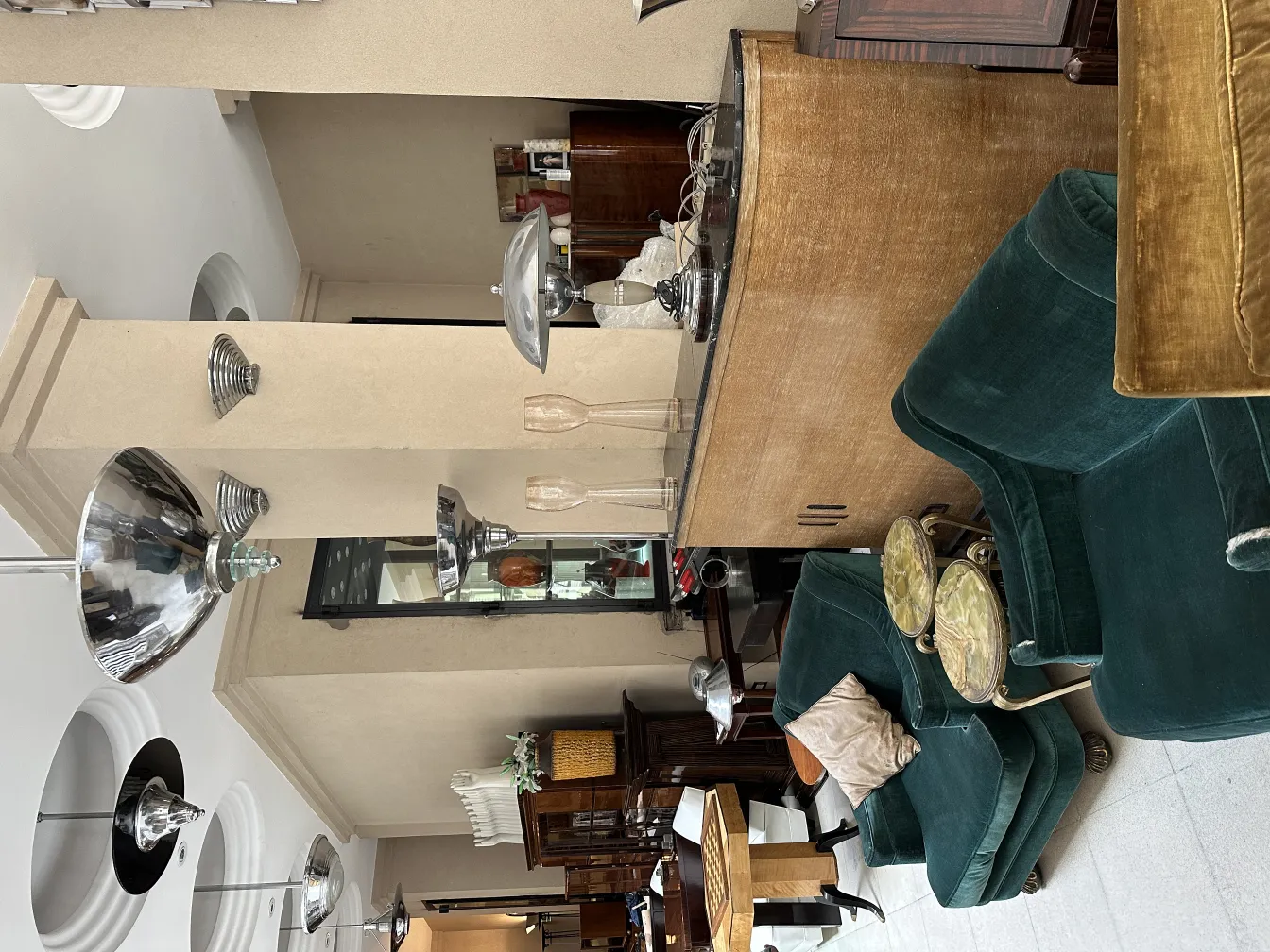 Pair of antique sconces with a shiny finish, elegantly designed within a vintage ambiance featuring varied furniture.