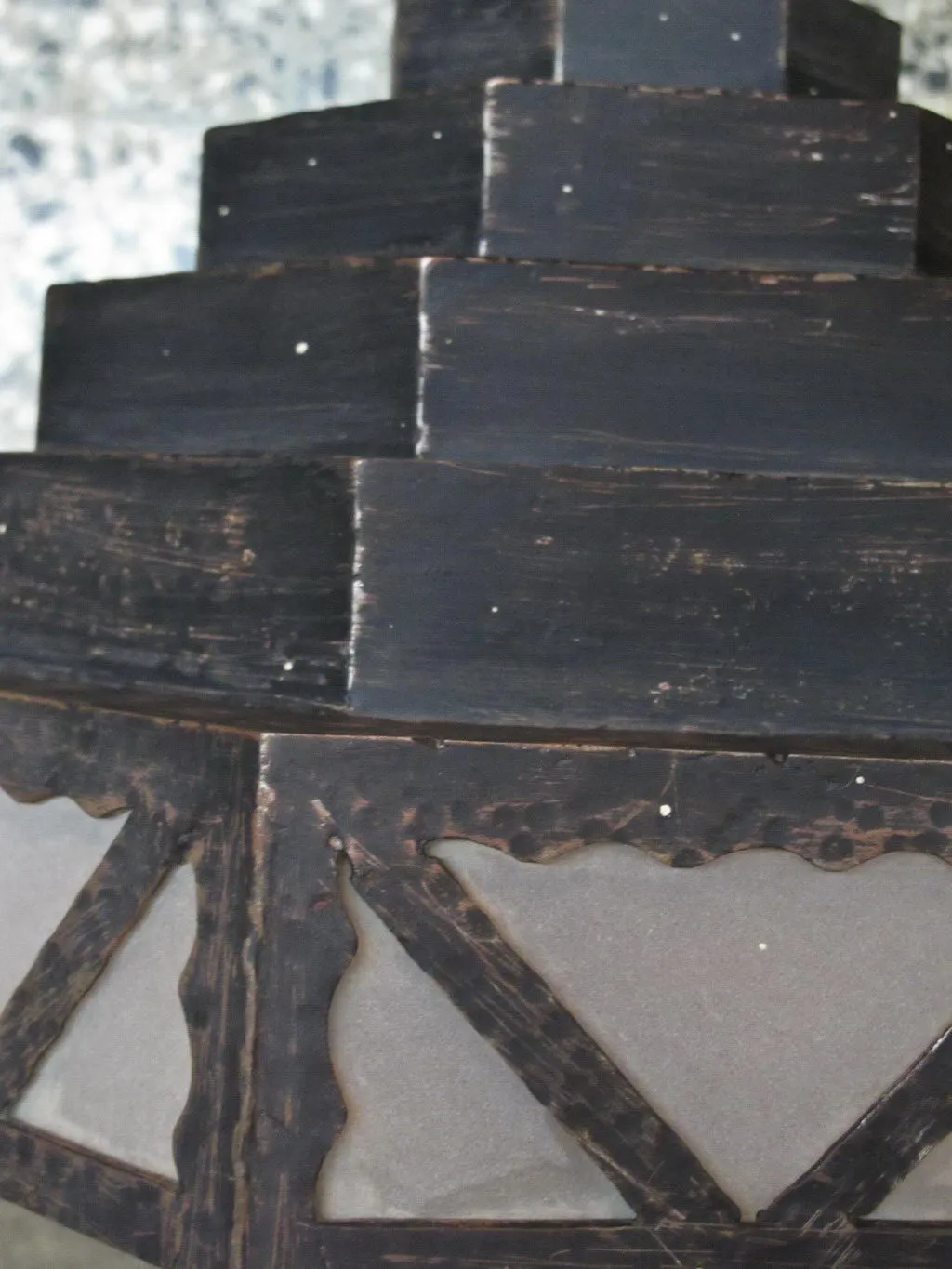 Antike Wandleuchter mit dekorativem Design und dunklen Details an einer hellen Wand.