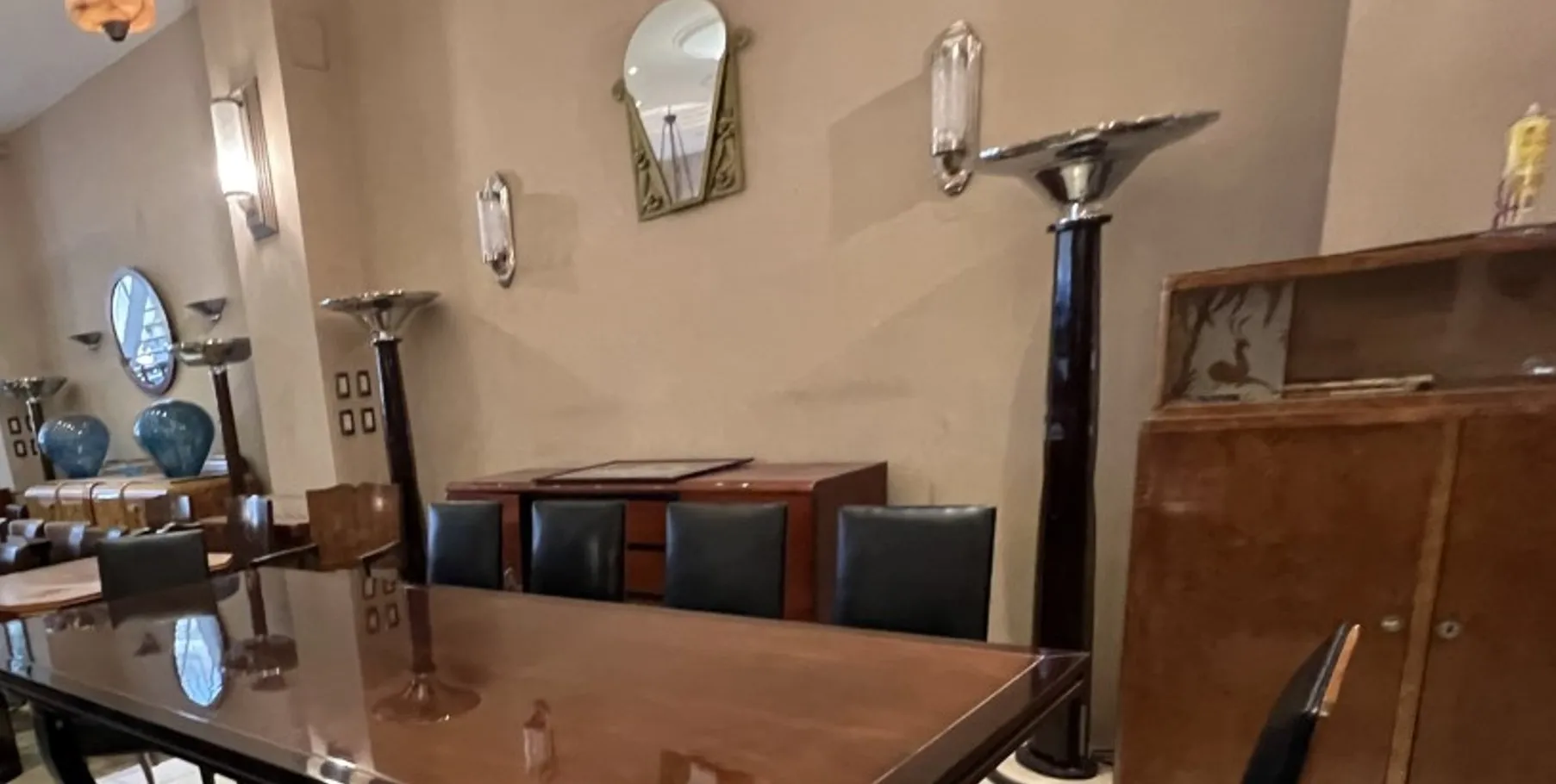 Paire d'appliques antiques dans un cadre élégant avec une table en bois et des chaises noires.