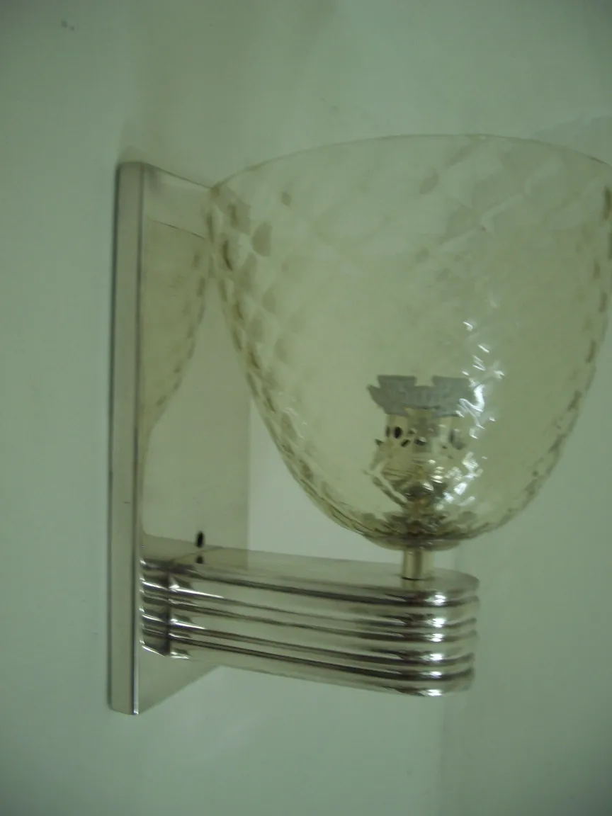 Coppia di applique antiche con design in vetro sfaccettato montate su una parete bianca.