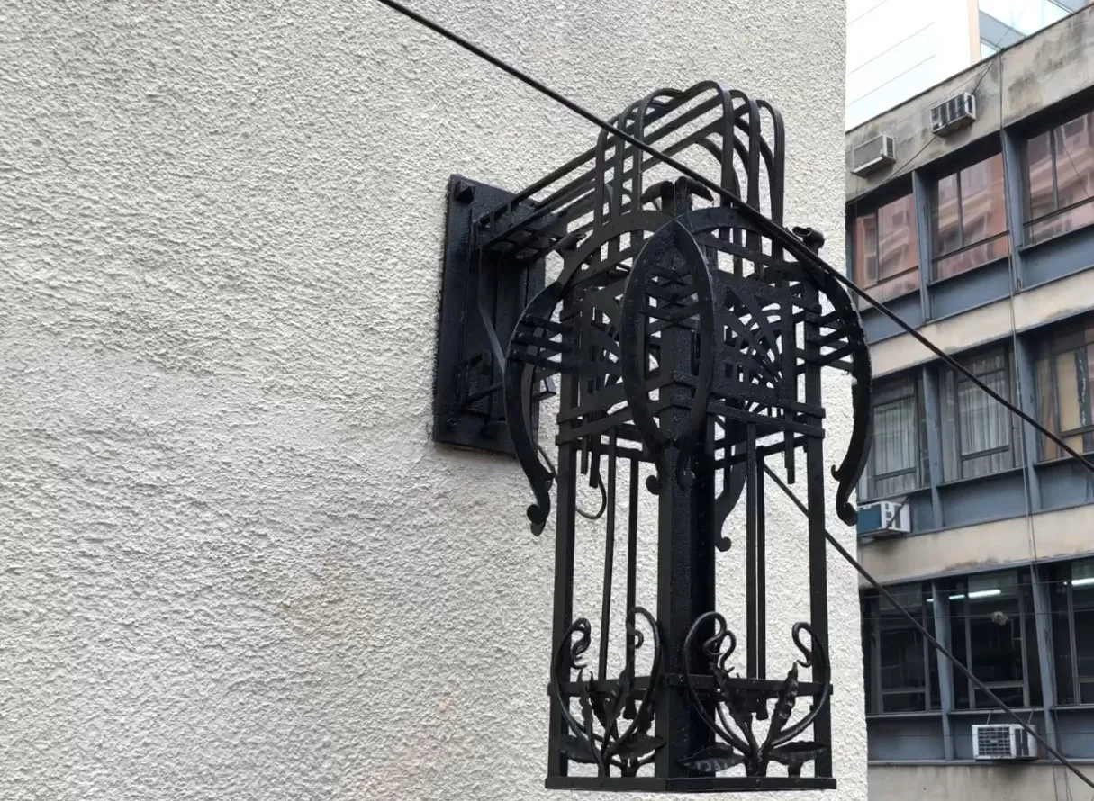 Coppia di applique antiche con design eleganti in nero, montate su una parete chiara in ambiente urbano.