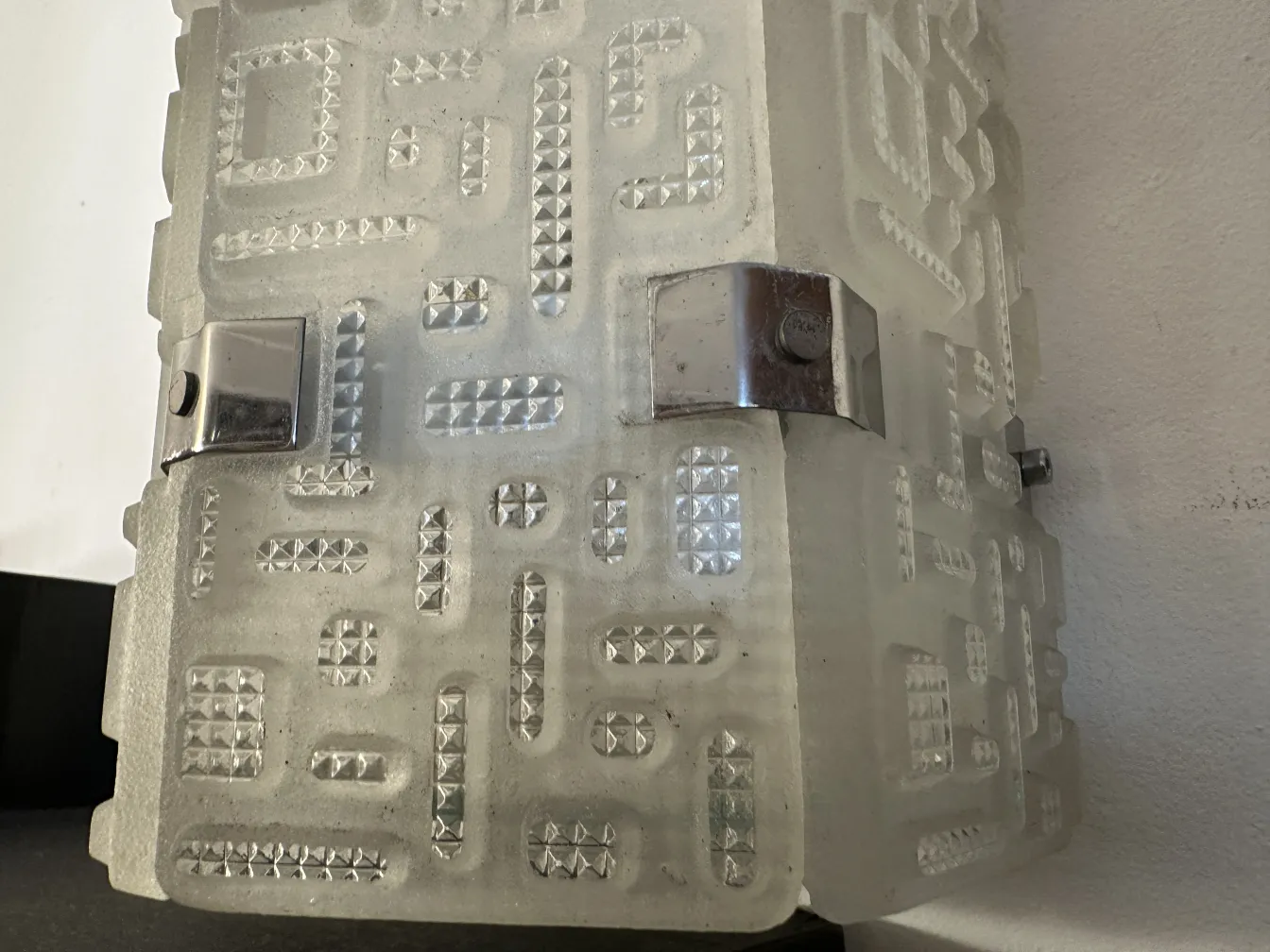 Dekorativer antiker Wandleuchter mit geometrischem Design in hellen Tönen.