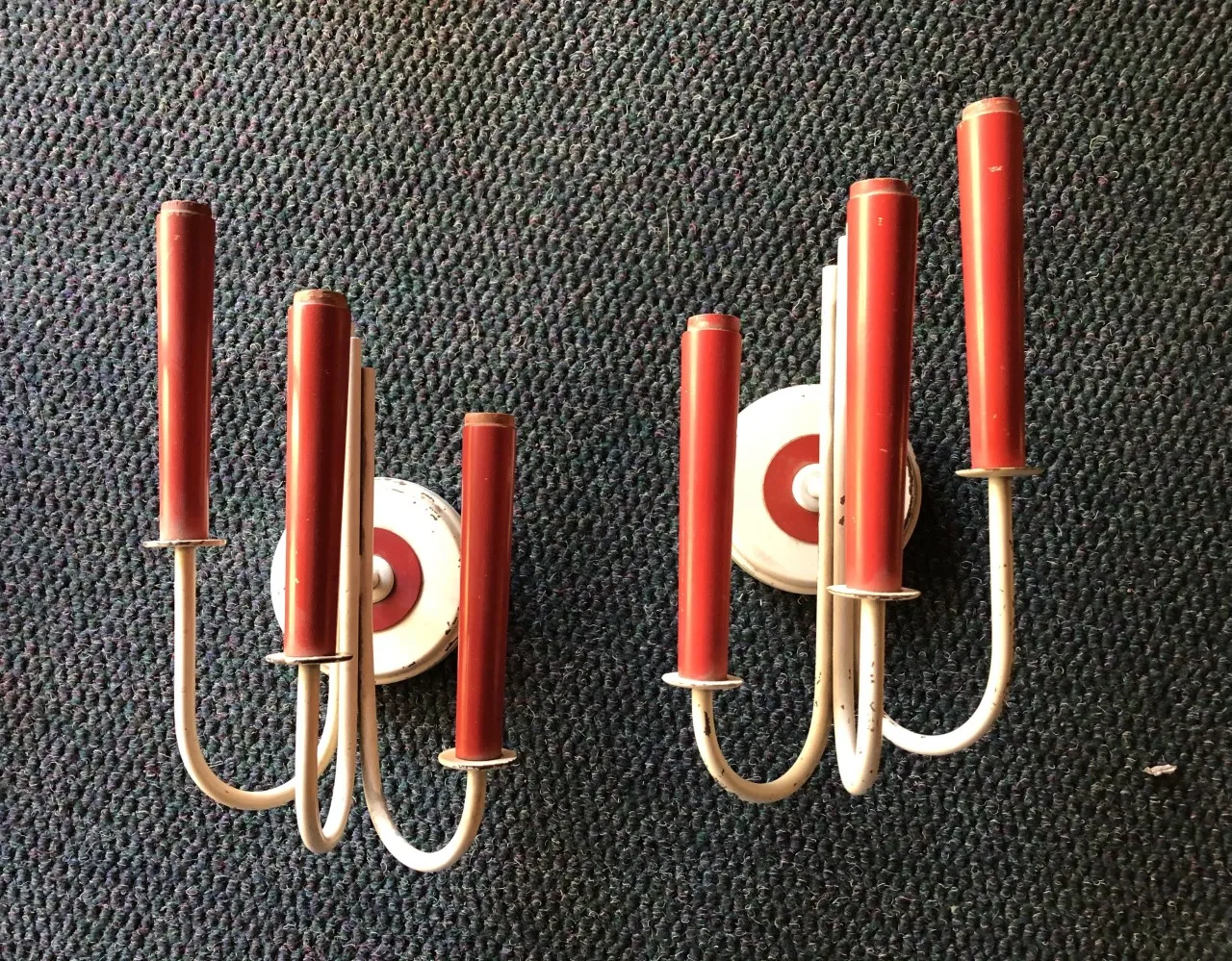 Coppia di applique antiche con luci rosse e basi bianche, in ambiente neutro.