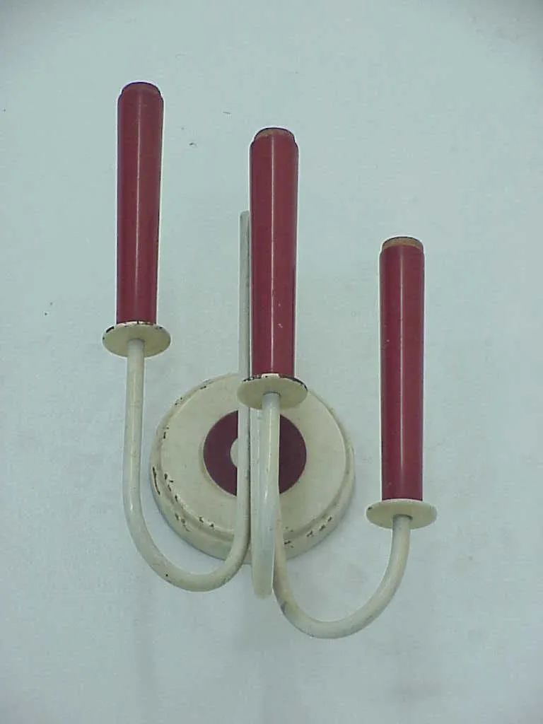 Antique pair of sconces featuring curved arms and red details in a simple background.