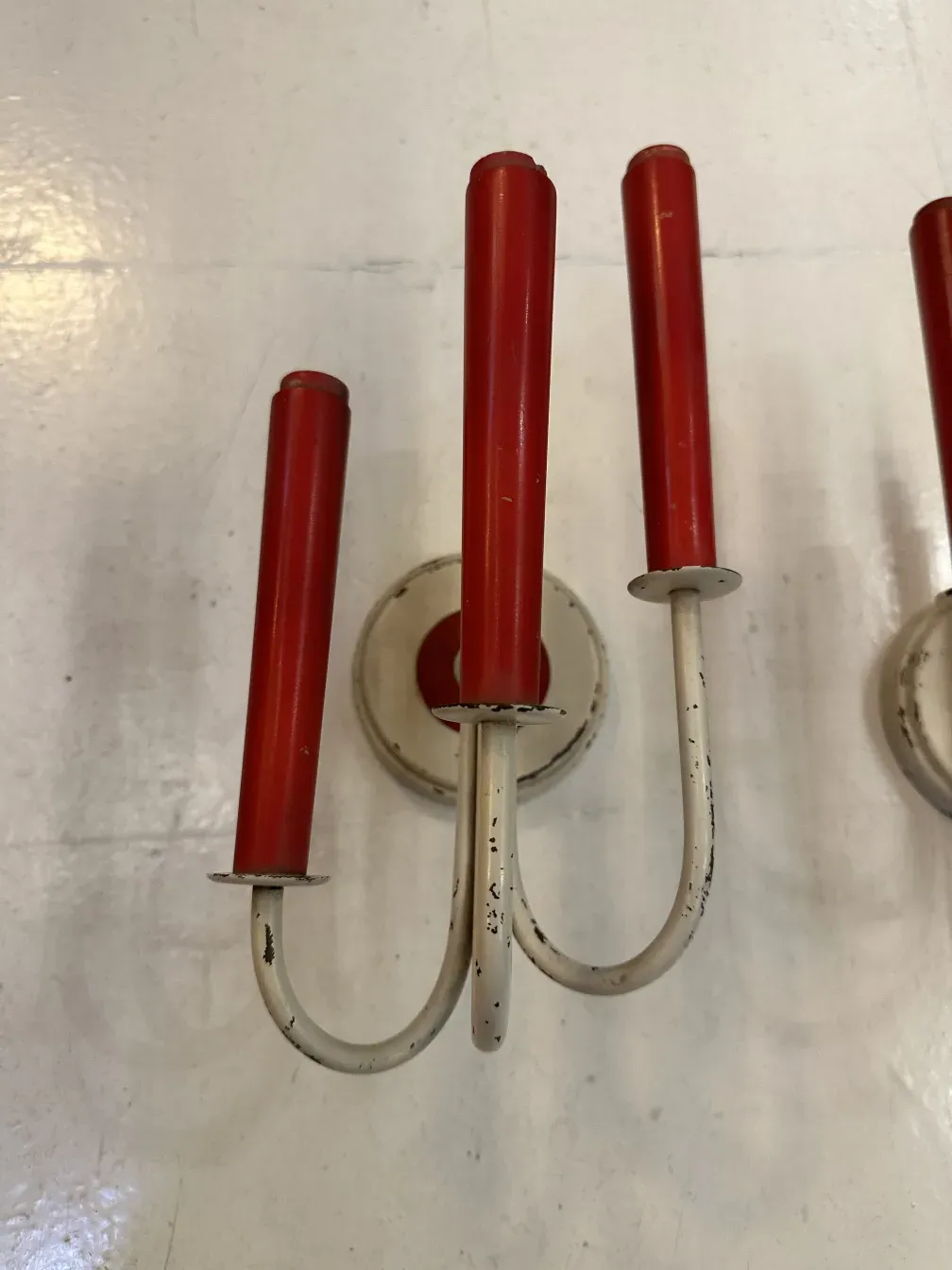 par de luminárias de parede antigas com acabamentos vermelhos e formas estilizadas em um ambiente iluminado