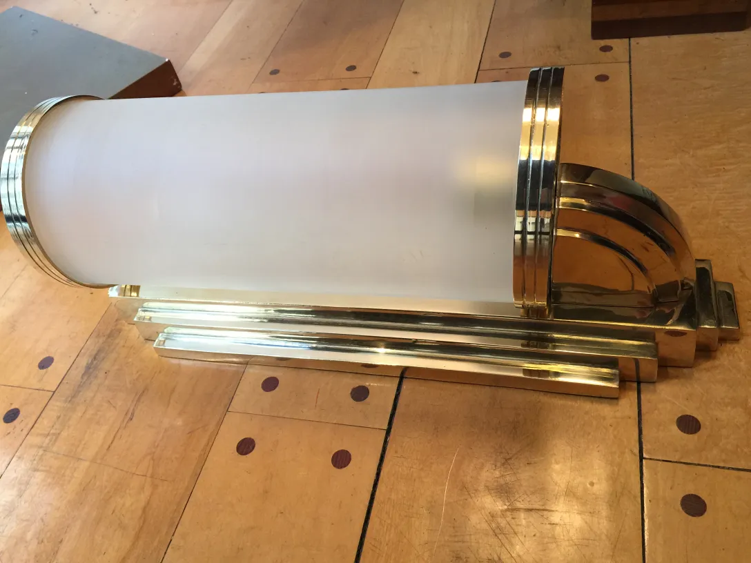 Par de luminárias de parede antigas com acabamento dourado e vidro fosco em um ambiente clássico.