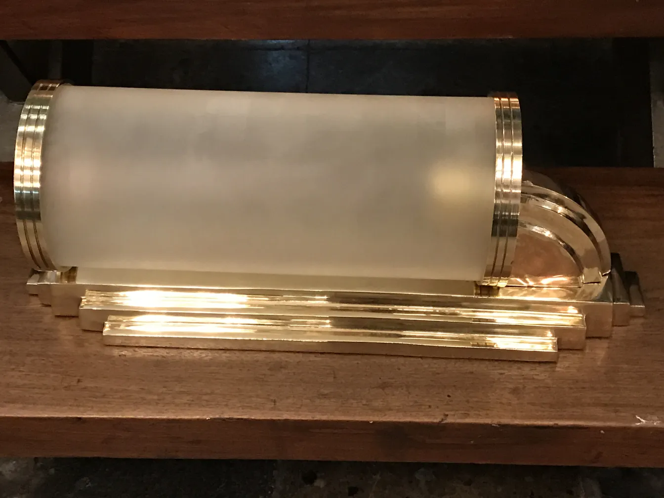 Par de apliques antiguos con detalles dorados sobre fondo de madera