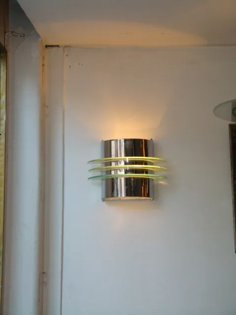 Applique murale antica con dettagli giallastri e finitura lucida, illuminando l'ambiente.