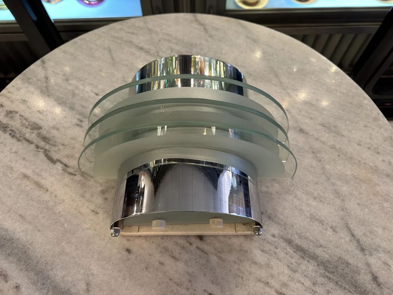 Antiguo par de apliques con diseño contemporáneo, de cristal y metal, en una mesa de mármol.