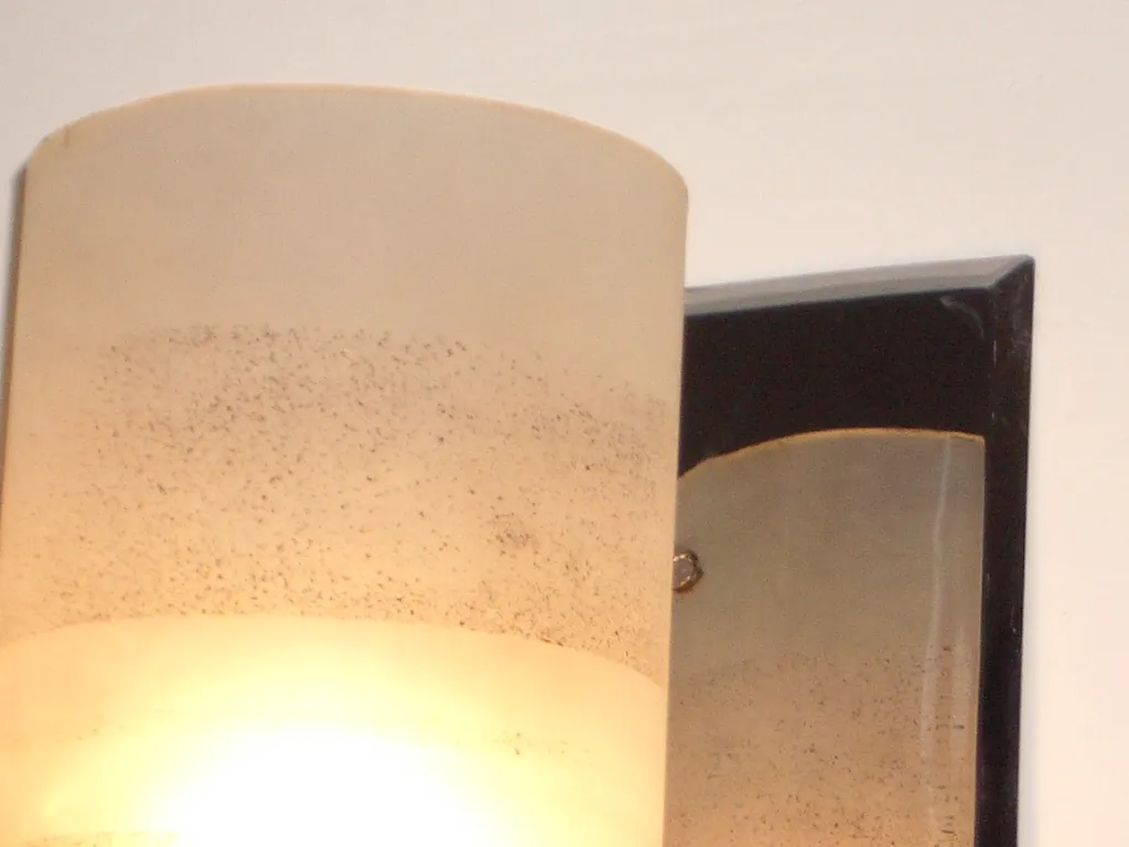 Coppia di applique antiche con paralumi diffusori che illuminano una parete bianca.