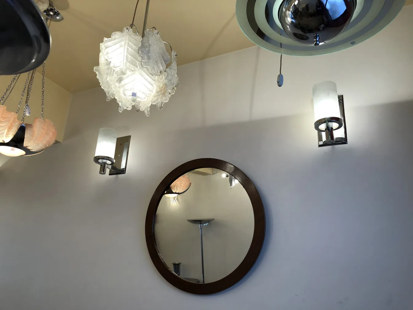 Par de luminárias antigas com luz suave na parede, ao lado de um espelho.