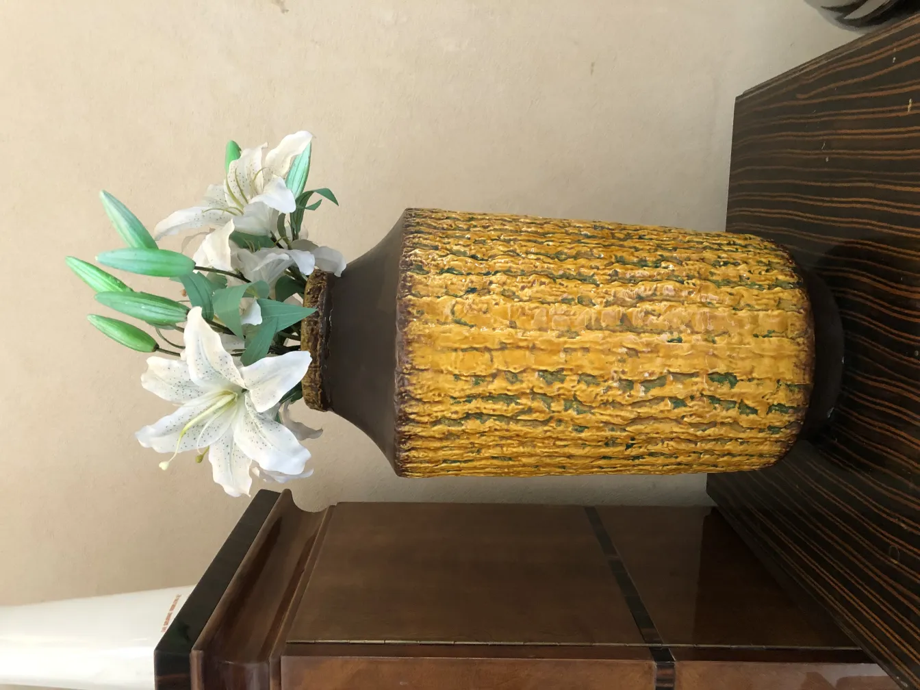 Vaso di ceramica antica con fiori bianchi e foglie verdi.