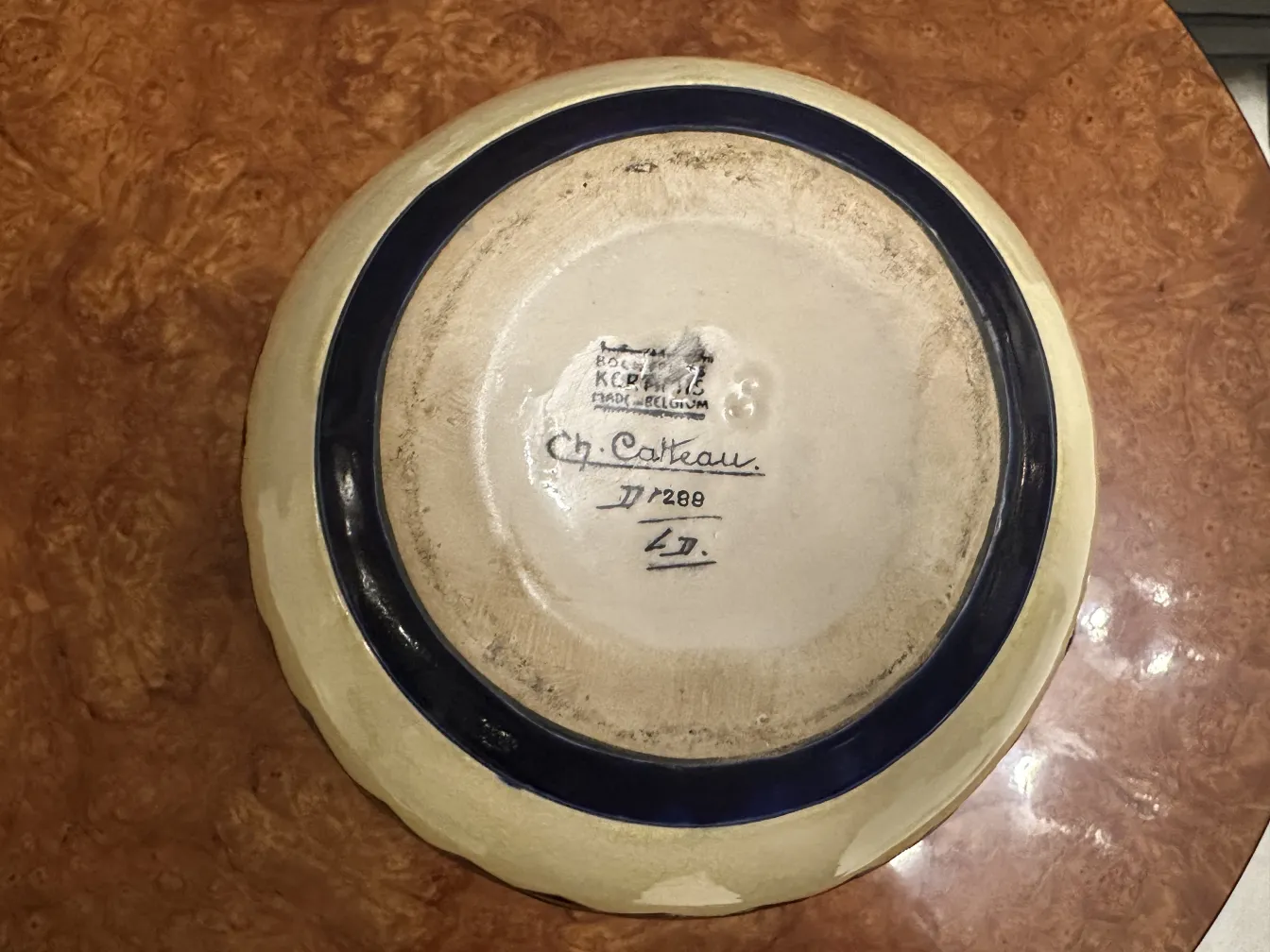 Plato de cerámica antigua con borde azul en fondo blanco.