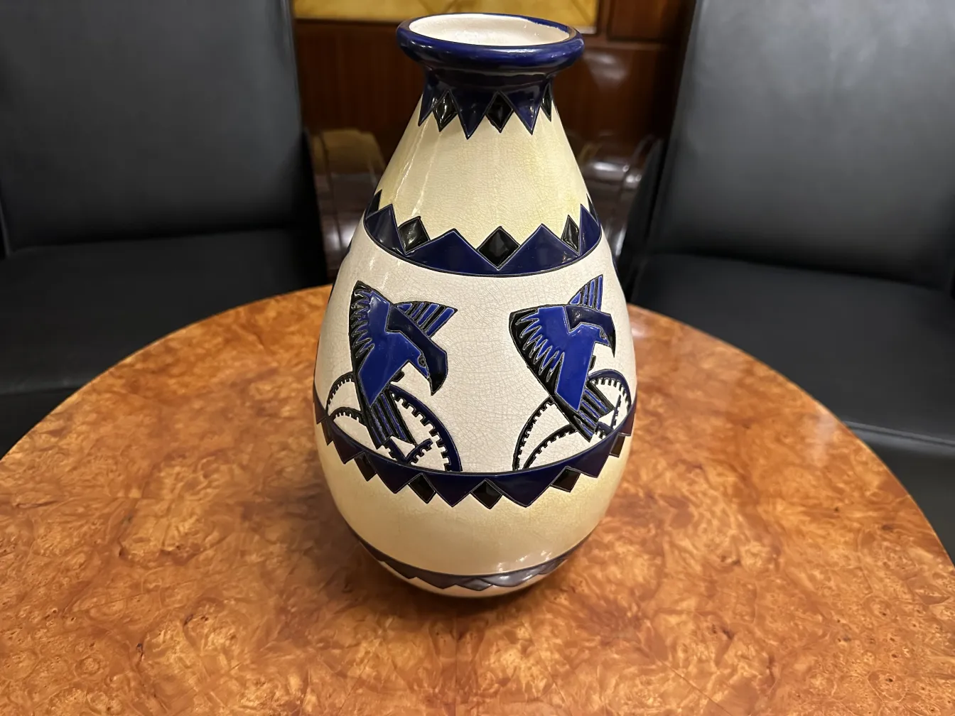 Vaso di ceramica antica decorato con uccelli blu su sfondo chiaro.