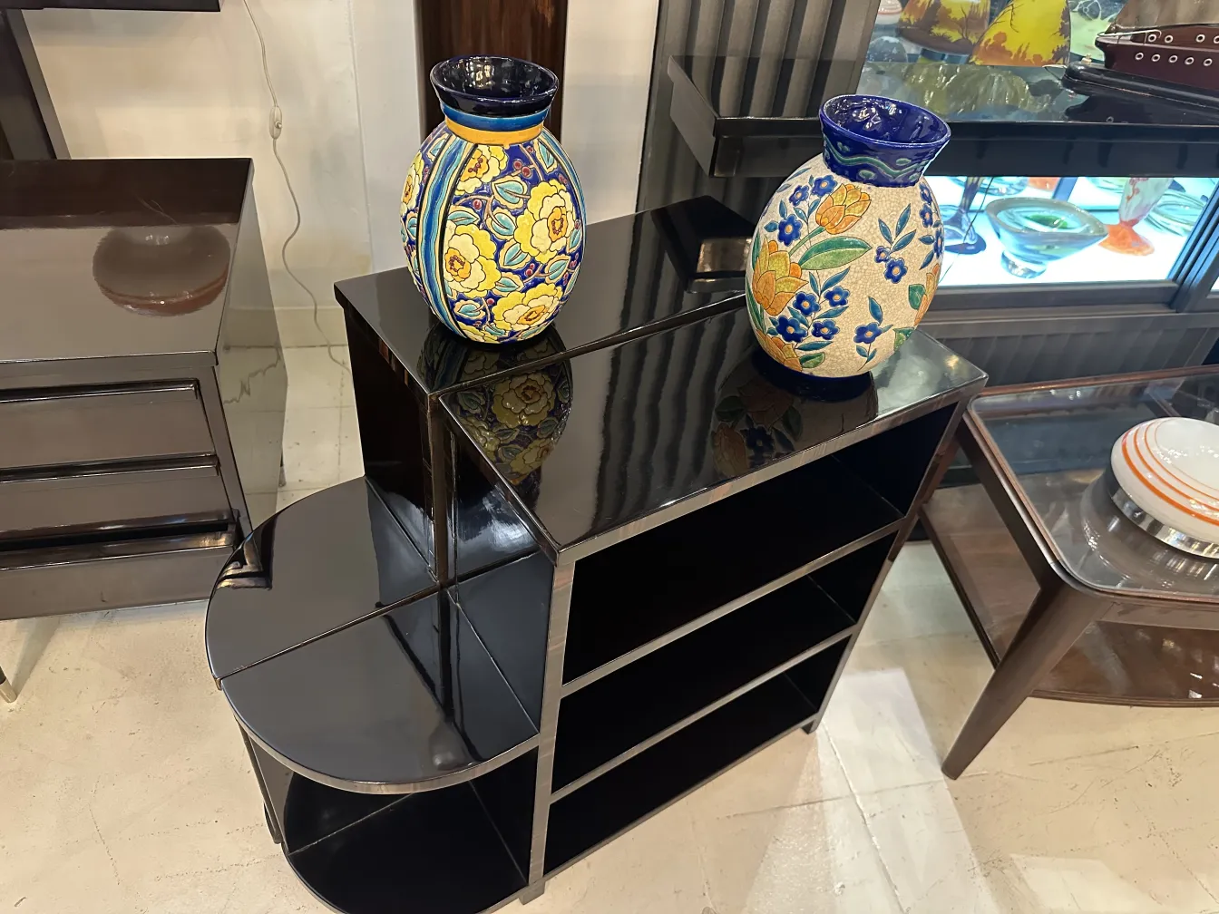 Dos jarrones de cerámica antigua con flores en una estantería.