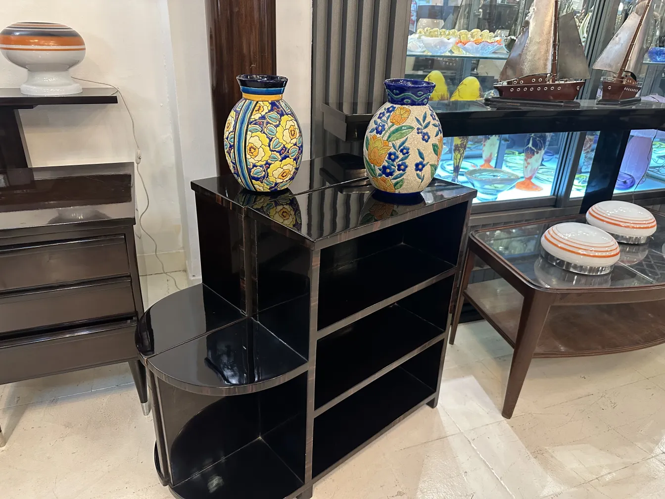 Deux vases en céramique ancienne Boch Frères Keramis aux couleurs vives sur une étagère noire.