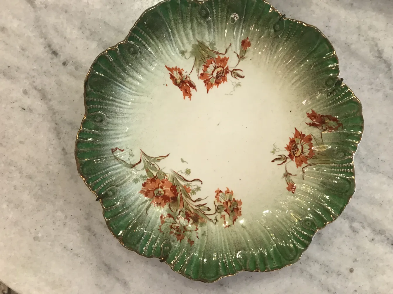 Plato antiguo de cerámica con flores en relieve y borde verde