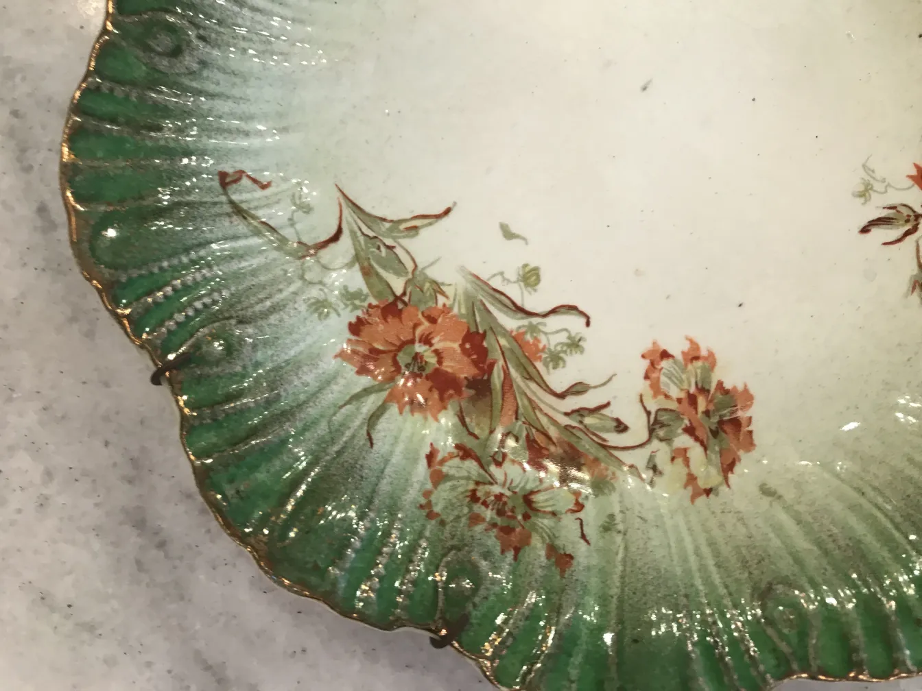 Piatto antico di ceramica con decorazione floreale e verde.