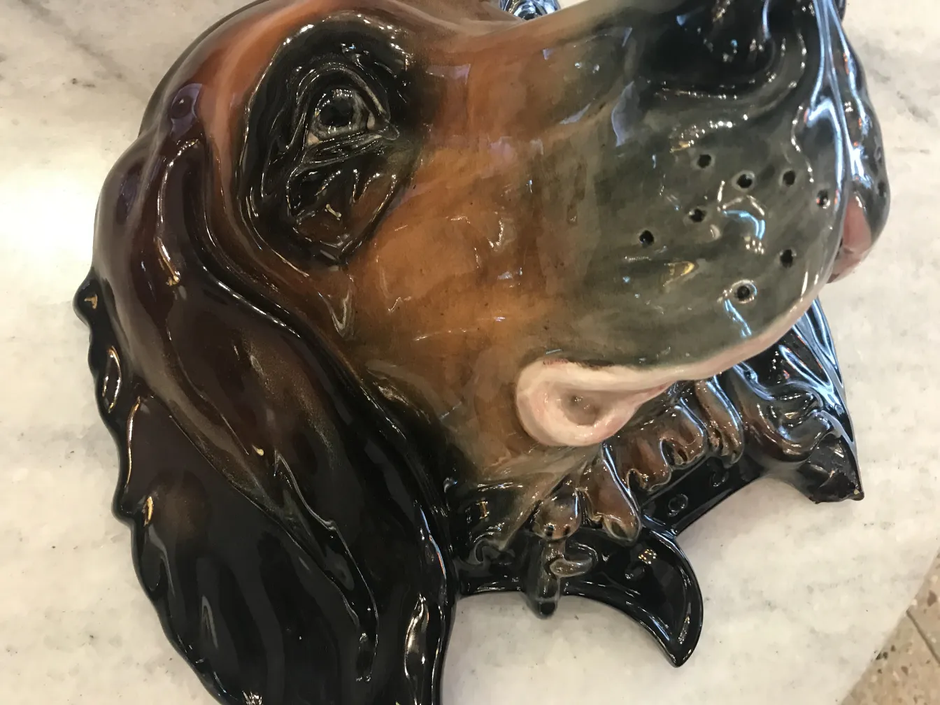 Escultura antiga de cachorro em cerâmica, com detalhes em marrom e preto.