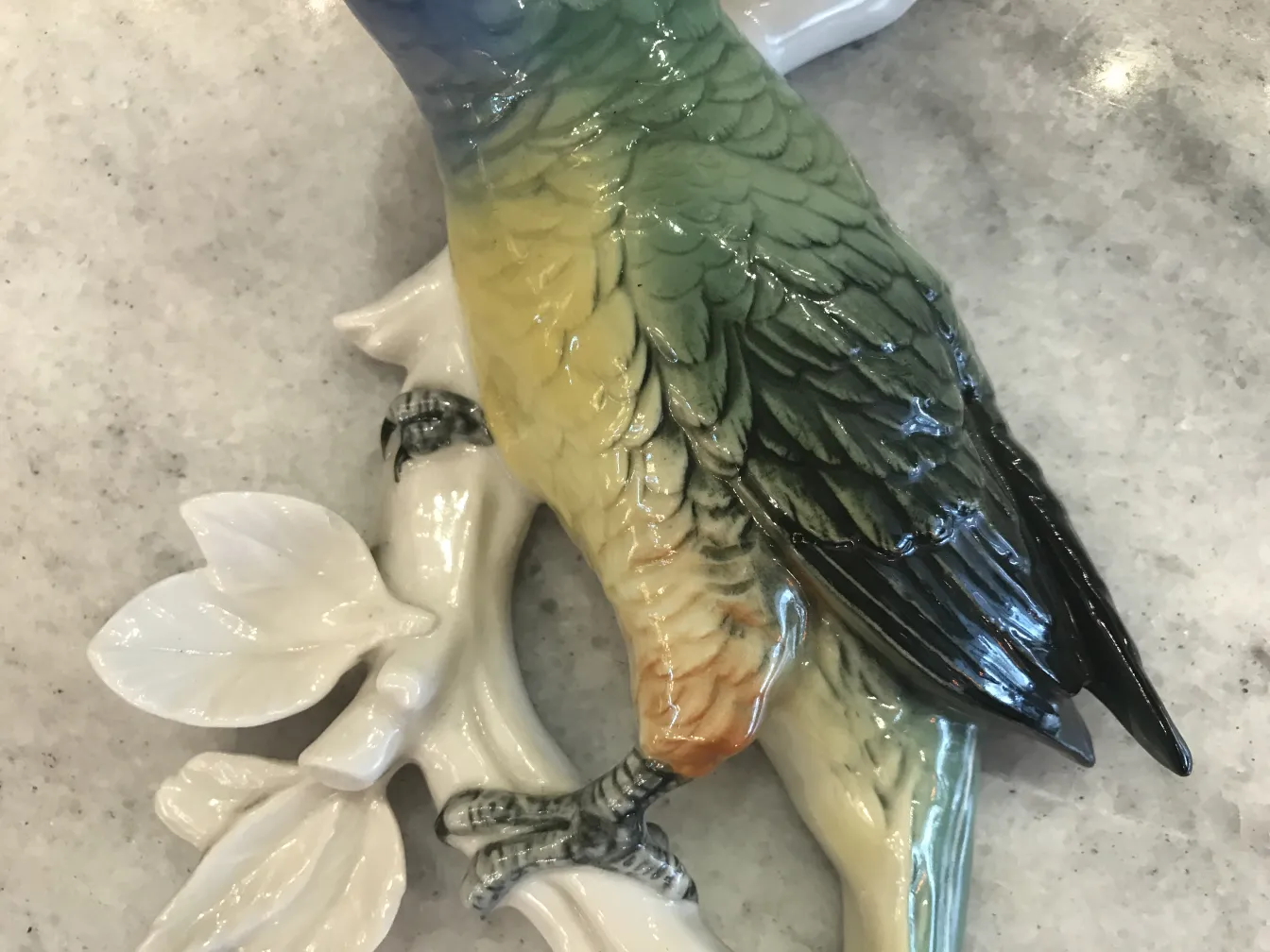 Escultura de cerâmica antiga de um pássaro colorido em um galho.