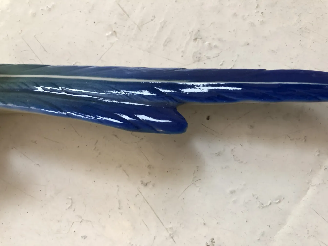 Cerámica antigua de color azul con un diseño fluido en un fondo claro.