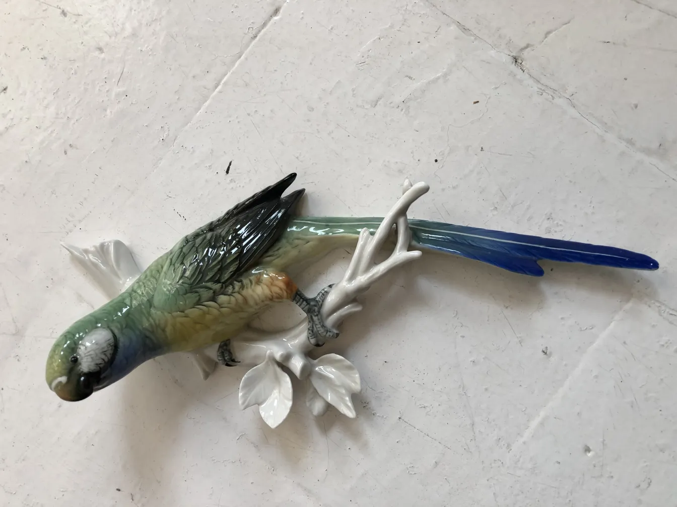 古董陶瓷鸟雕塑栖息在树枝上。