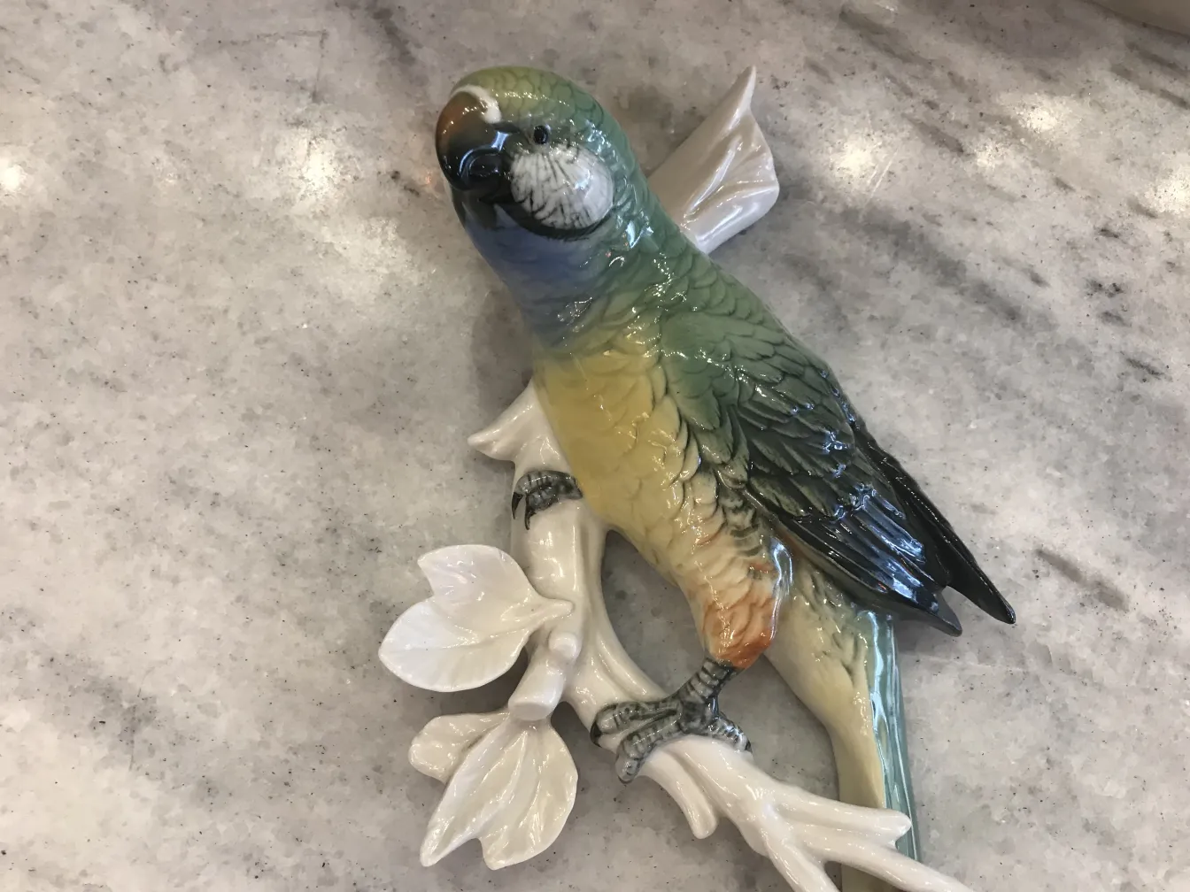 Escultura antiga de cerâmica de um pássaro colorido em galhos.