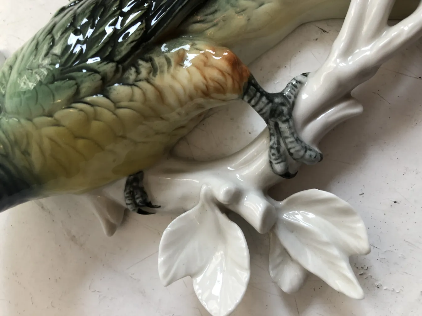 Figura de cerâmica antiga de uma ave em ramo decorativo.