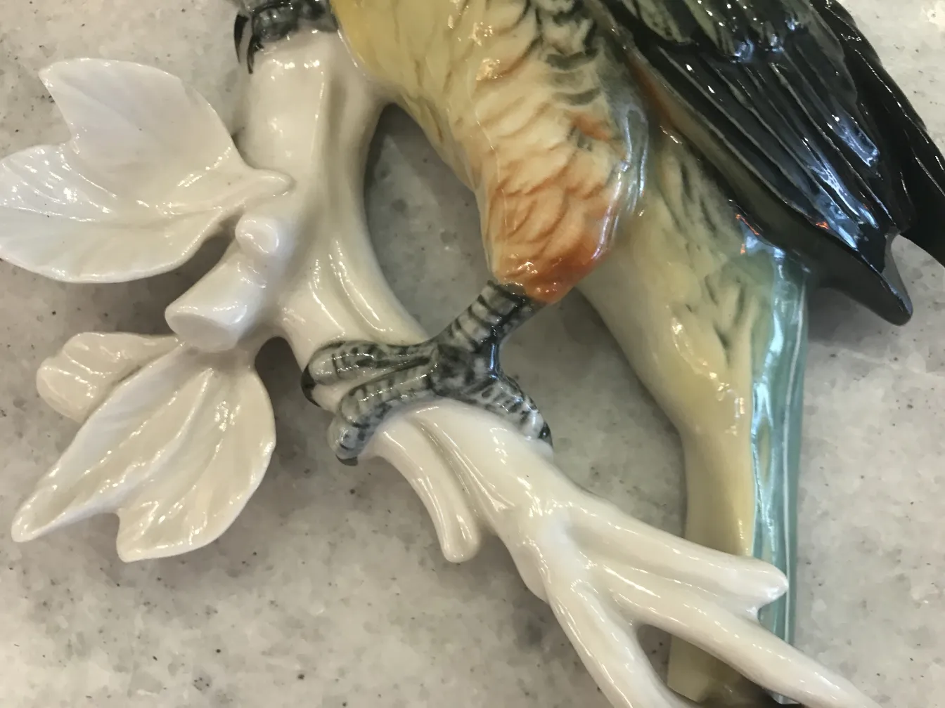 Figure d'oiseau ancienne en céramique sur des feuilles blanches