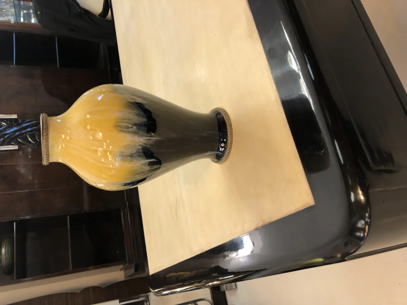 Vase en céramique ancien avec motif jaune et noir sur une table claire.