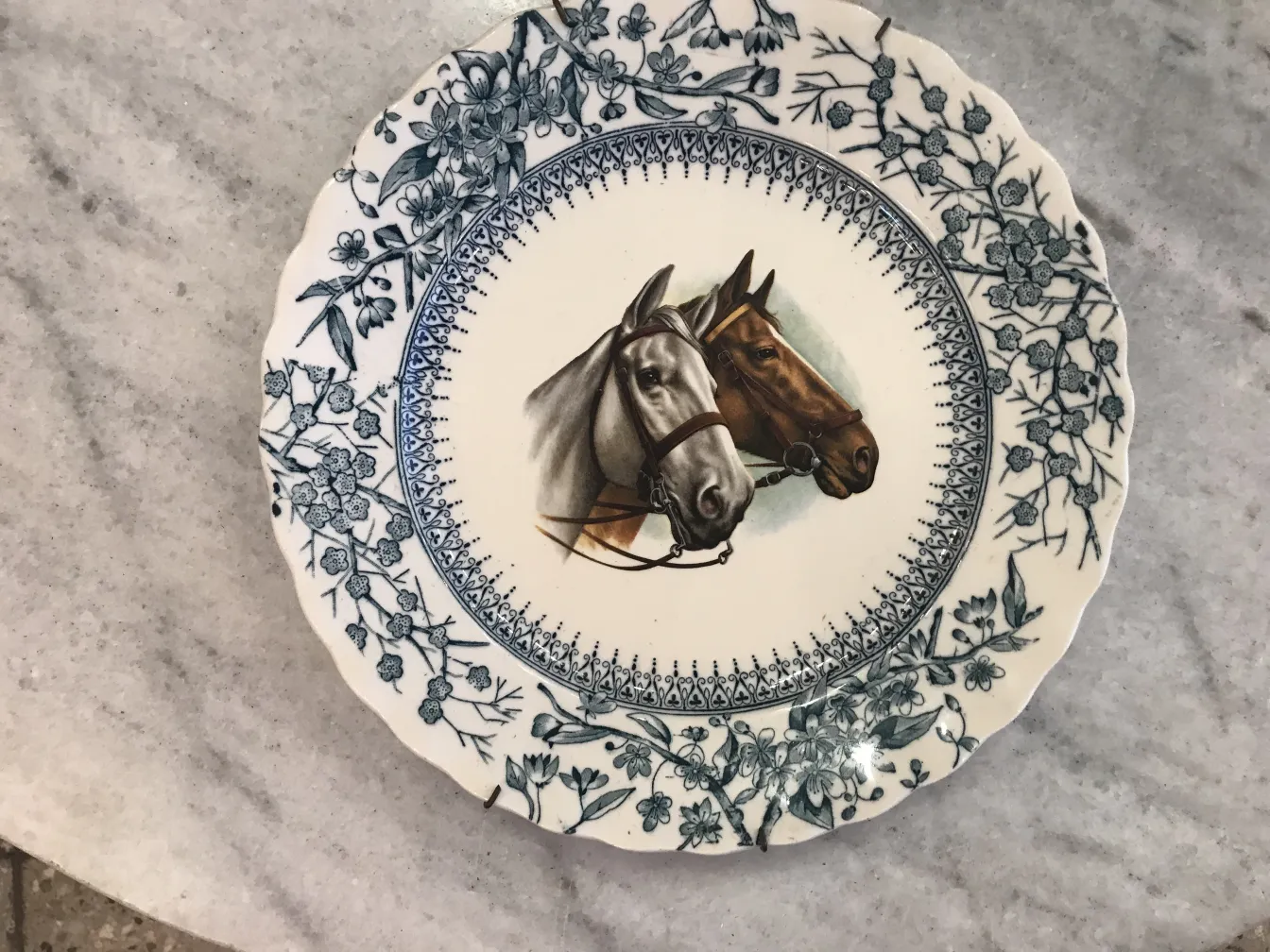 Assiette en céramique ancienne avec deux chevaux au centre.