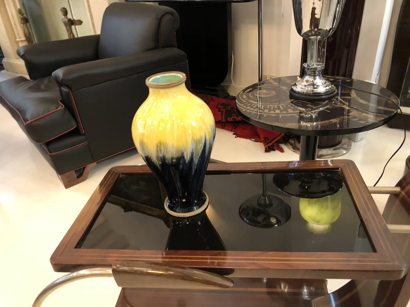 Vaso decorativo antigo em cerâmica amarelo e azul sobre uma mesa elegante, em um ambiente aconchegante.