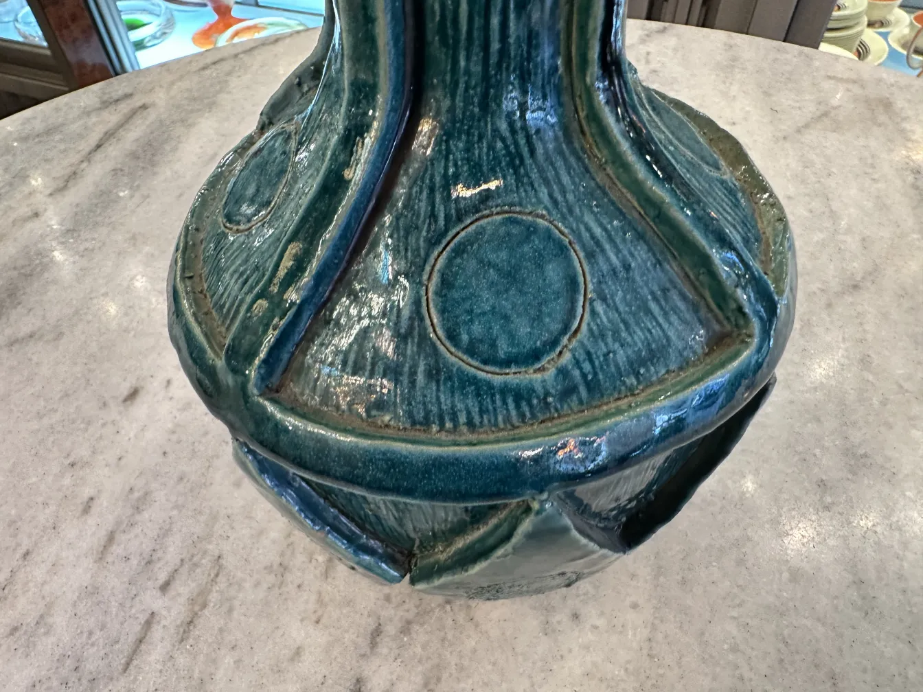 Antique ceramic vase in blue with circular details on a light surface.