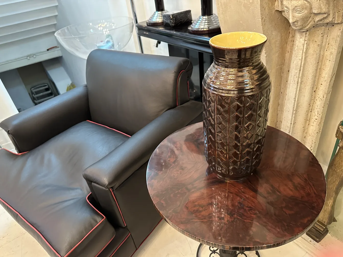 Vaso de cerâmica antiga decorativa em mesa marrom, ambiente elegante.