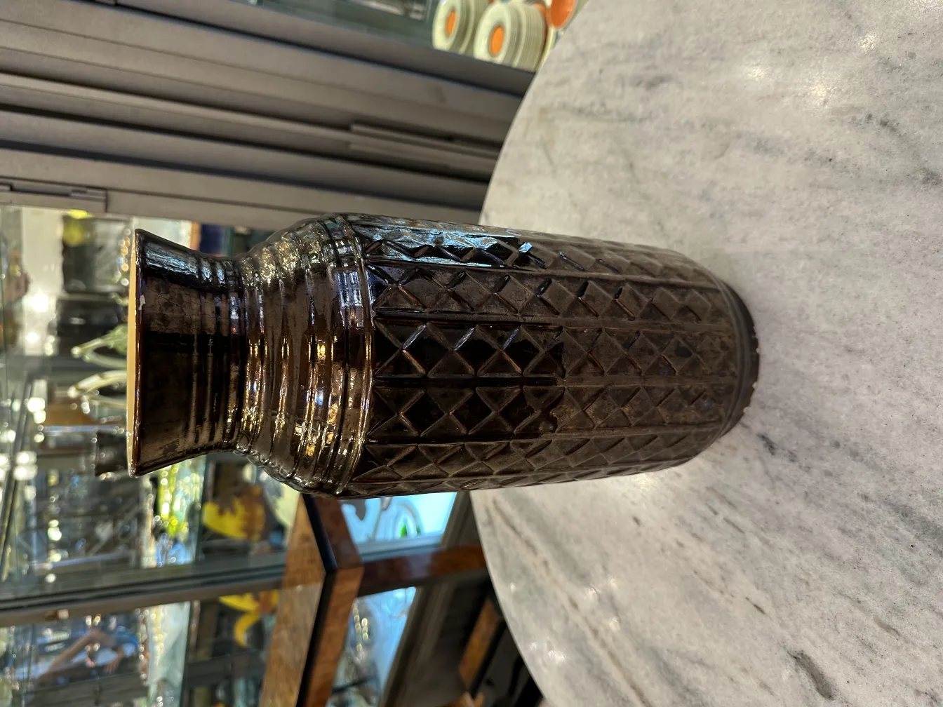 Vase en céramique ancienne avec design géométrique foncé.