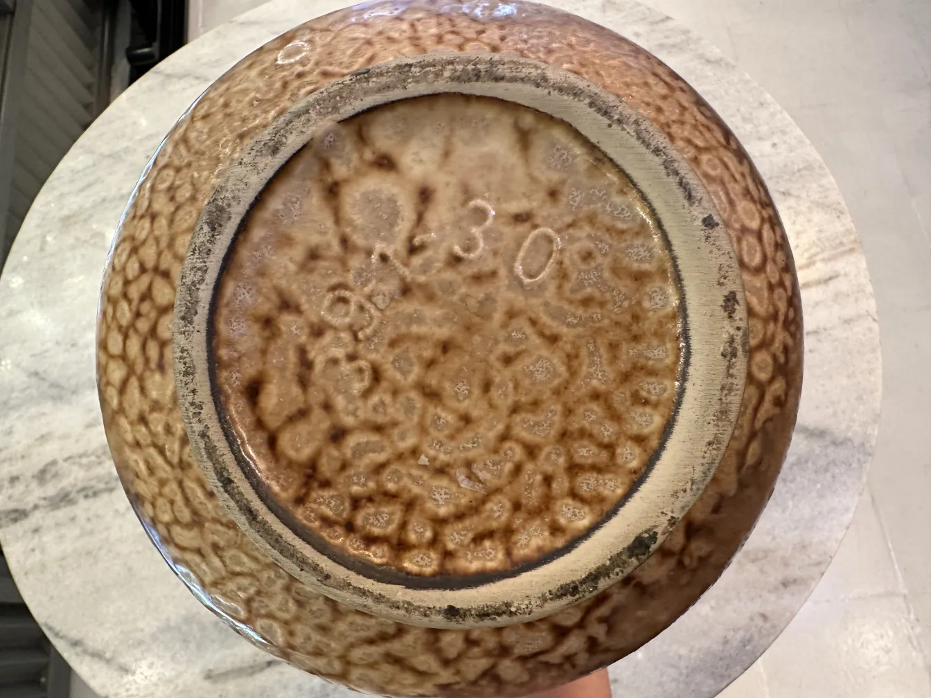 Tigela de cerâmica antiga com textura em relevo marrom.