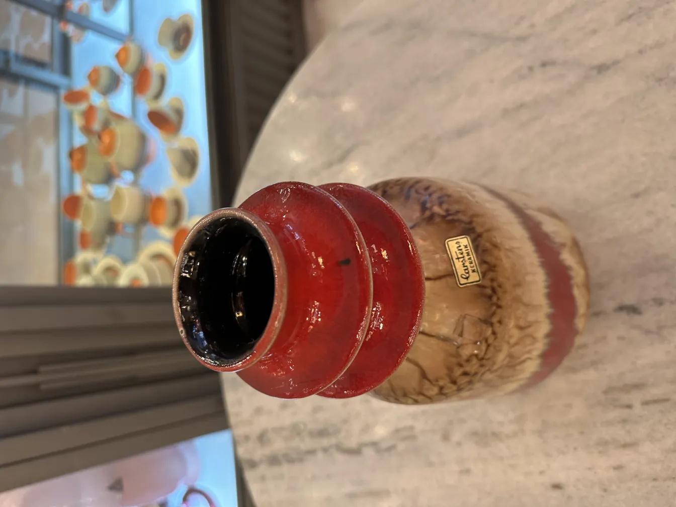 Jarrón de cerámica antigua con tonos rojos y beige, decorativo.