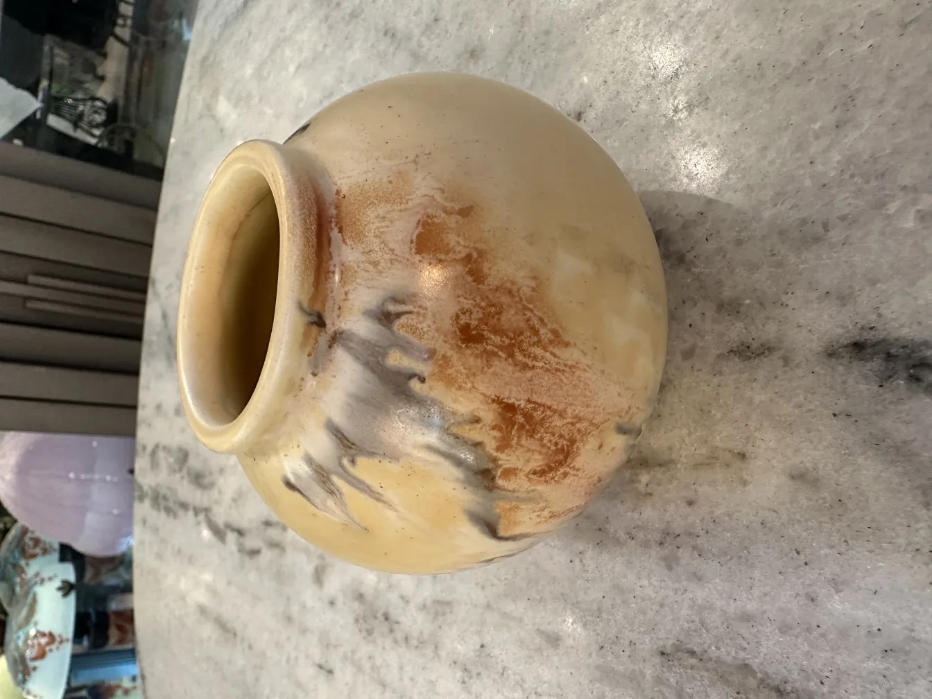 Jarrón antiguo de cerámica con tonos terrosos sobre mesa