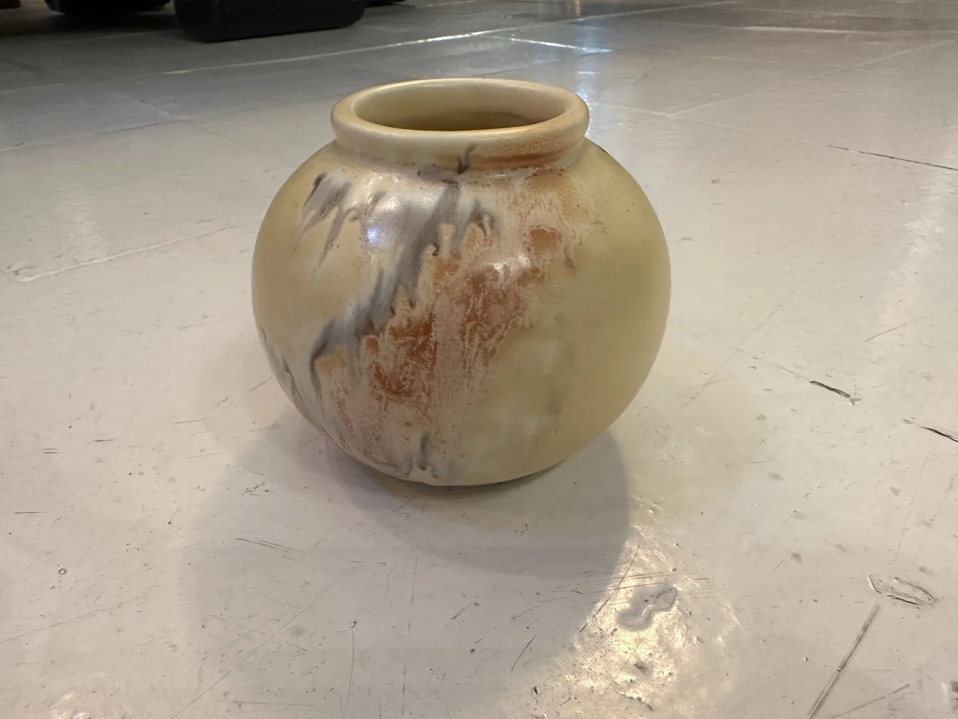 Vase en céramique avec des tons beiges et des détails subtils, lumières et ombres mises en avant.