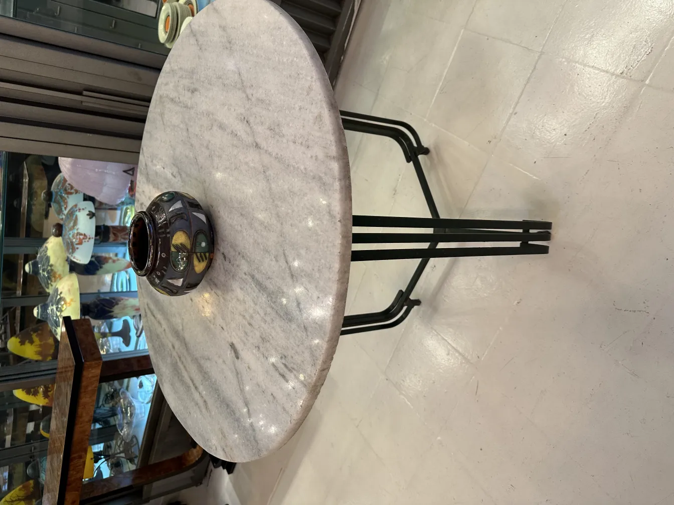 Antique artisan ceramic on a white table with black base.