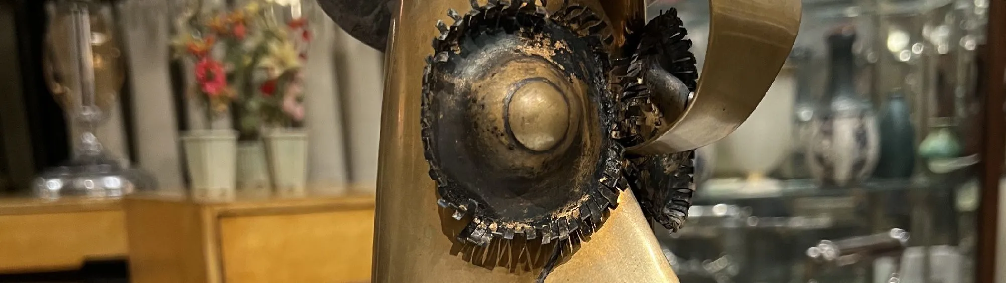 Escultura abstracta metálica con detalles únicos y formas fluidas, en un ambiente vintage.