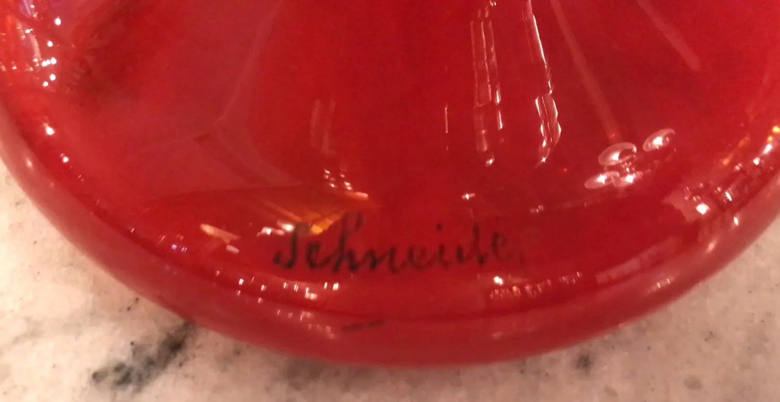 Antico sigillo Schneider rosso brillante, visibile su superficie chiara.